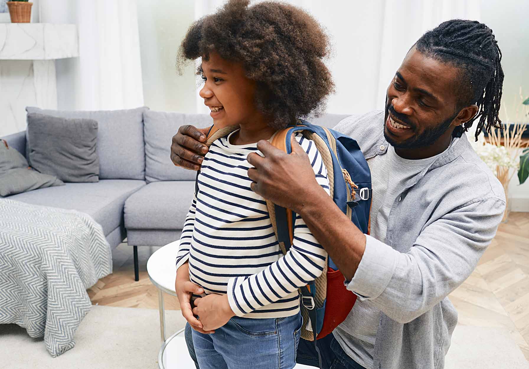 Father helps son put on his back-pack for the first day of school